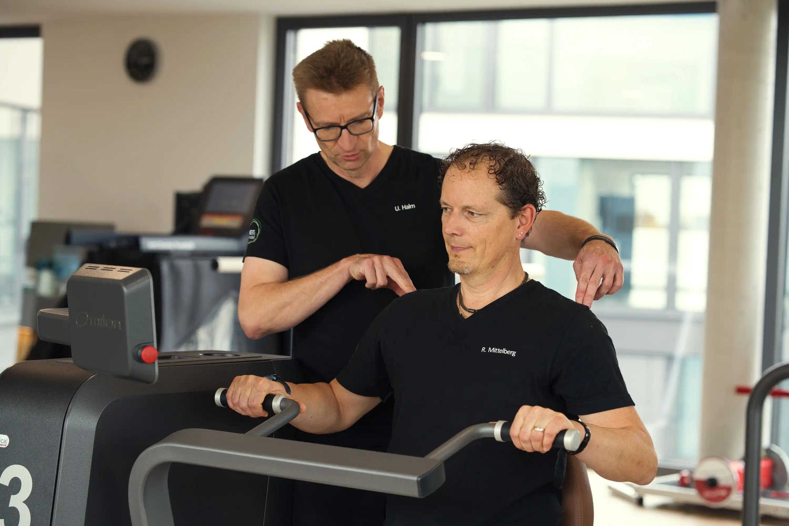 Krankengymnastik am Gerät Männlicher Patient wird von Physiotherapeut bei der Krankengymnastik am Gerät betreut